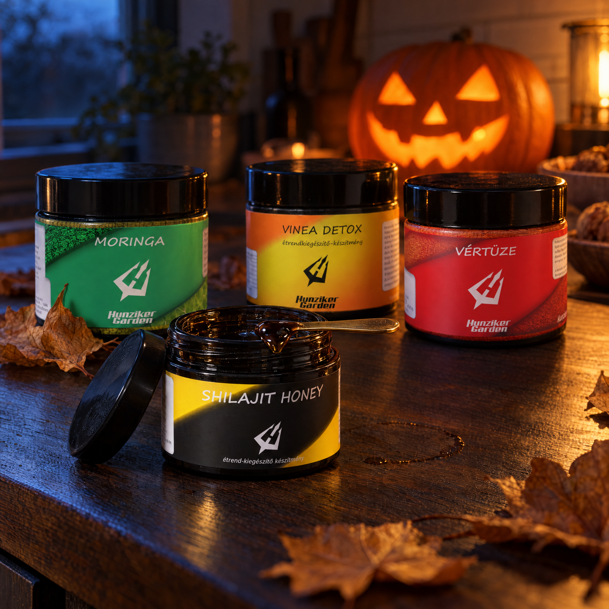 Halloween csomag: Shilajit Méz, Moringa, Vinea Detox és Vértüze egy konyhapulton, mögöttük világító faragott tök