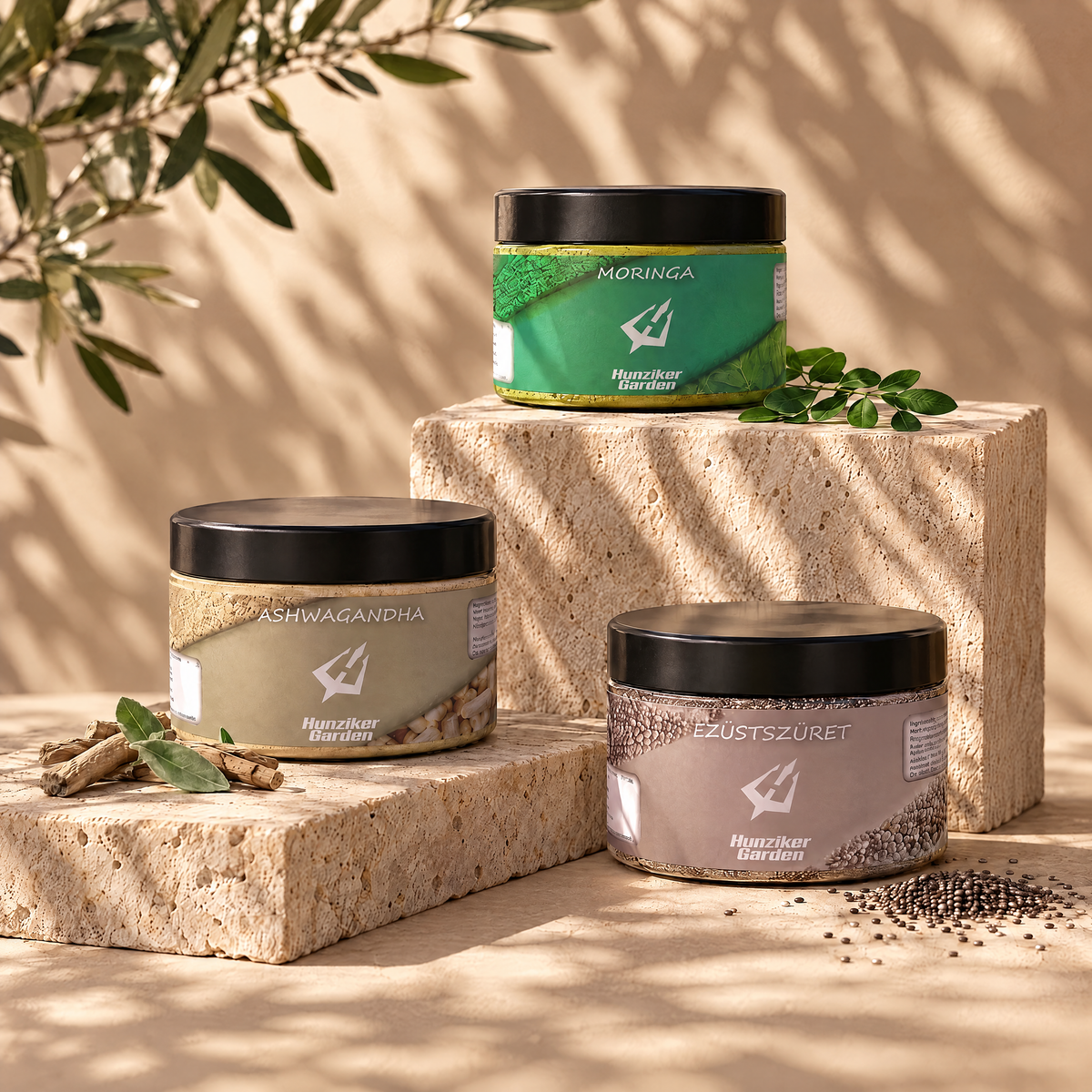 A HunzikerGarden csomag három tégelye travertin kőtömbökön, olajfalevelek árnyékában, mellettük friss moringa levél, ashwagandha gyökér és chia mag