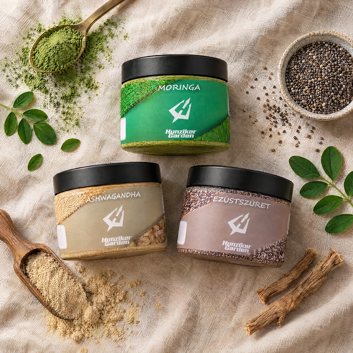 Felülnézeti kép a Moringa, Ashwagandha és EzüstSzüret tégelyről len terítőn, körülöttük moringa por, ashwagandha por és gyökér, valamint chia mag