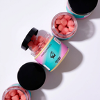 Négy tégely Hunziker Garden hajvitamin esztétikus elrendezésben; a nyitott tégelyekben láthatók a rózsaszín, cukorral bevont gumicukrok.